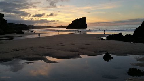 Scenic view of beach against dramatic sky during sunset