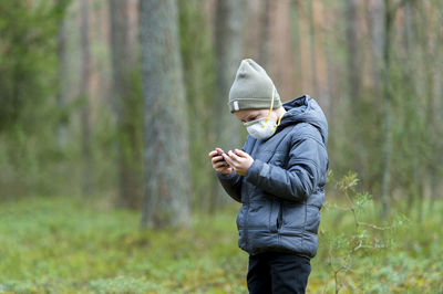 Man holding mobile phone in forest