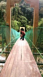 Rear view of woman sitting on footbridge