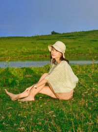 Portrait of young woman sitting on field against wonderful blue sky