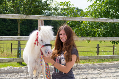 Portrait of happy woman with pony standing in ranch