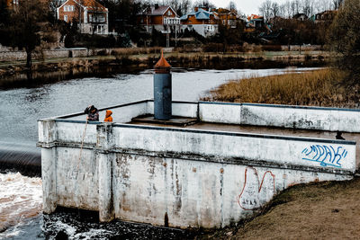 Man sitting by river against building