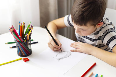 Boy drawing on book at home