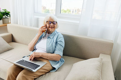 Young woman using laptop while sitting on sofa at home