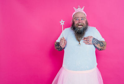 Portrait of man standing against pink background