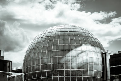 Low angle view of modern building against cloudy sky