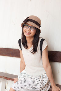 Smiling young woman sitting against wall