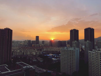 Modern buildings against sky during sunset