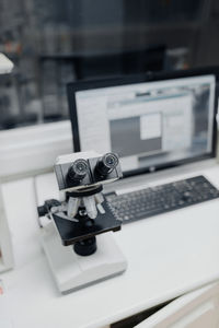 From above of microscope near computer with open program on screen in vet laboratory