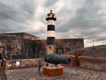 Rear view of boy by cannon against cloudy sky at southsea castle