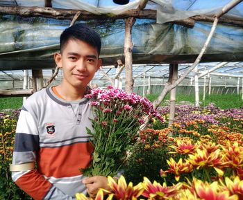 Portrait of young man standing on flowering plants