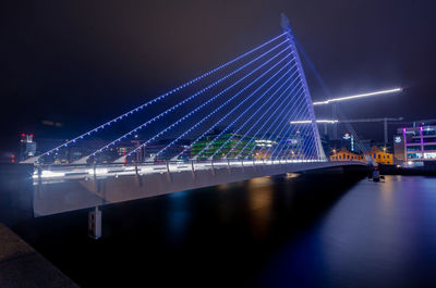 Illuminated bridge over river at night