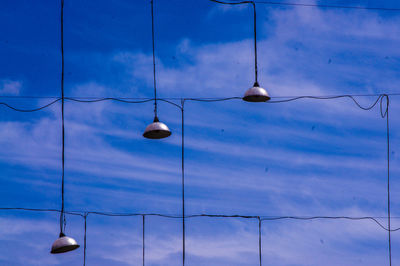 Illuminated lighting equipment hanging against blue sky