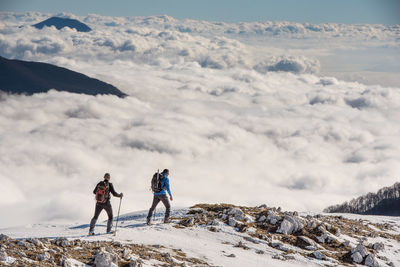 People on snowcapped mountain against sky