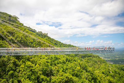 Bridge over road amidst trees against sky