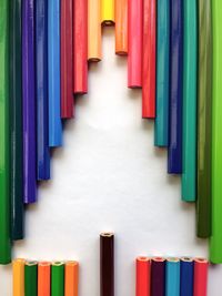 Close-up of colorful pencils shaping christmas tree on white table