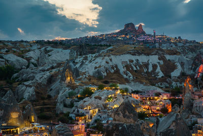 Aerial view of buildings on mountain against cloudy sky
