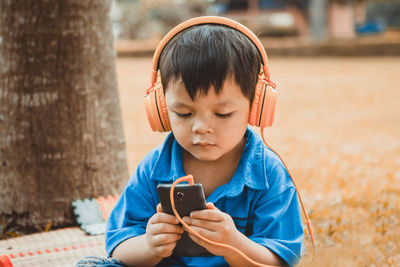 Cute boy watching movie in mobile phone outdoors