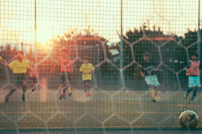 People playing soccer field against sky