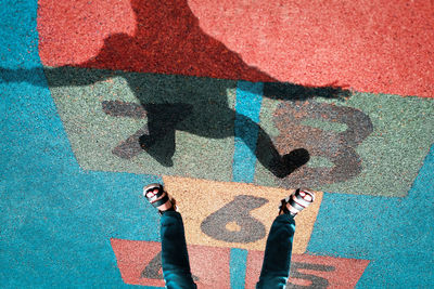 Low section of man standing on multi colored shadow