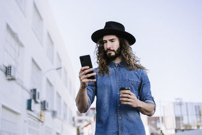 Young man photographing while using smart phone