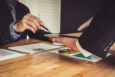 Midsection of man holding umbrella on table