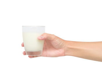 Close-up of hand holding beer glass against white background