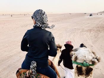 Rear view of people with dog on sand