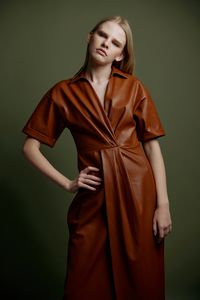 Portrait of young woman standing against wall