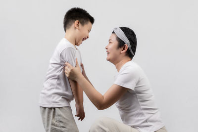 Side view of father and son against white background