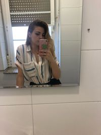 Portrait of young woman using phone while sitting on floor