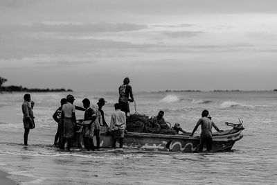 People on boat in sea against sky