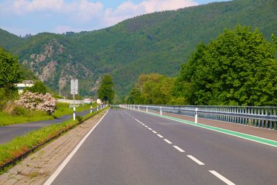 Road amidst trees and mountains against sky