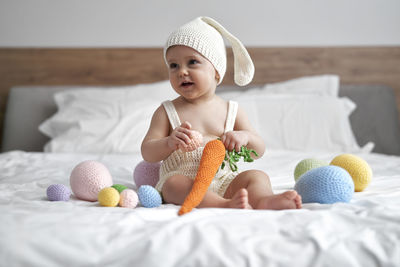 Smiling girl with toy sitting on bed