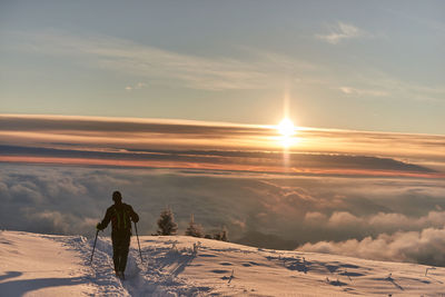 Man on snowcapped mountain against sky during sunset