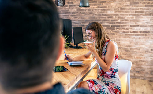 Woman using phone while sitting on table