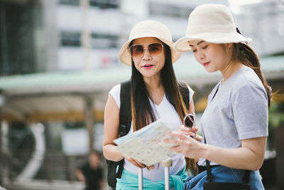 Tourists reading map while standing in city