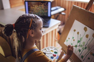 Side view of girl painting at home