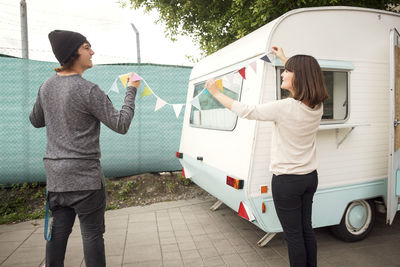 Rear view of male and female owners holding bunting by food truck on street