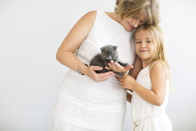 Grandmother and granddaughter with cat against white background