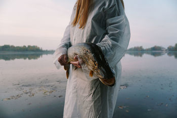 Midsection of young woman holding fish