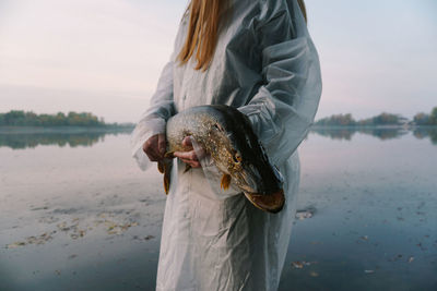 Woman standing by lake against sky