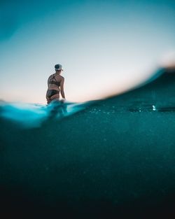 Man standing on rock by sea against sky