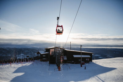 Overhead cable car on snowcapped mountains against sky