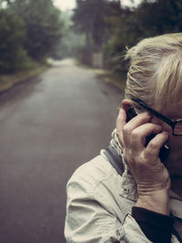 Cropped image of senior woman talking on mobile phone at road