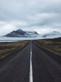 Road leading towards mountains against sky