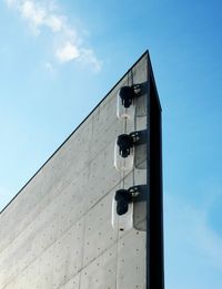 Low angle view of telephone pole against building in city against sky