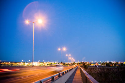 Light trails on illuminated bridge against clear sky at dusk