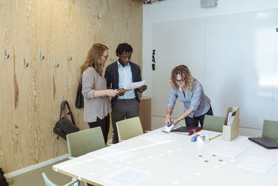 Male and female professionals working in board room at office