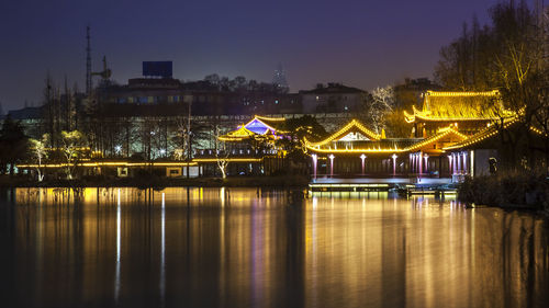 Illuminated bridge over river against sky at night